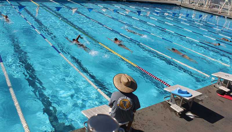 Men's swimming coach, Joe Abing, watches over the swim team as they are warming up. Abing prepares the team for the upcoming swim meet on Friday. Photo credit: Terrel Emerson