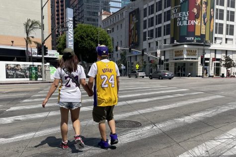 Tourist couple walking north from the Staples Center on Kobe Bryant day. They are crossing the sidewalk together wearing matching Kobe jerseys.