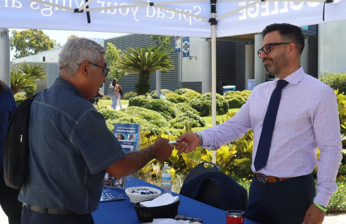 Rolando Garcia receiving a bookstore gift card from the Cerritos College President, Dr. Fierro, at his first President's Hour of the semester on Aug. 20 in front of the library.