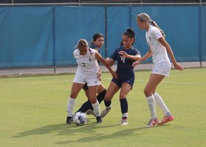 #7 Rubi Vazquez and #18 Madi Jones taking the ball from two Fullerton defenders