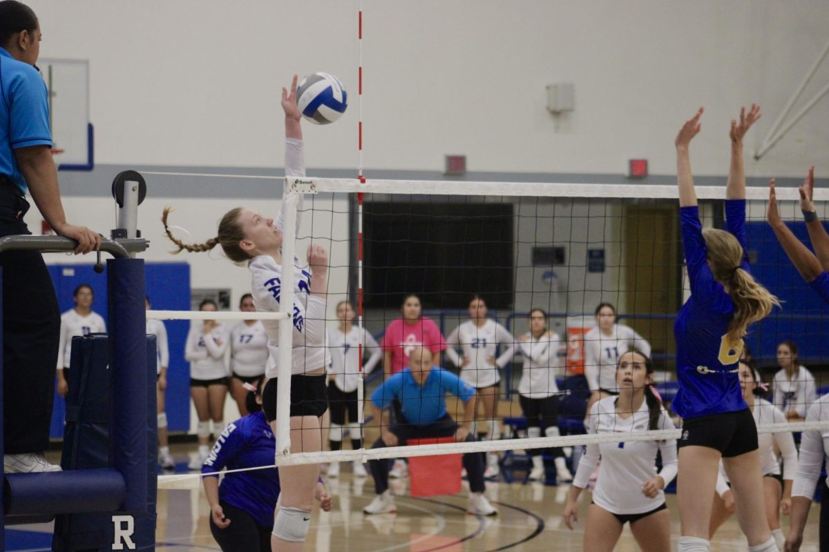 Syndney May spiking the ball with a defender across the net. Photo credit: Michael Delgado