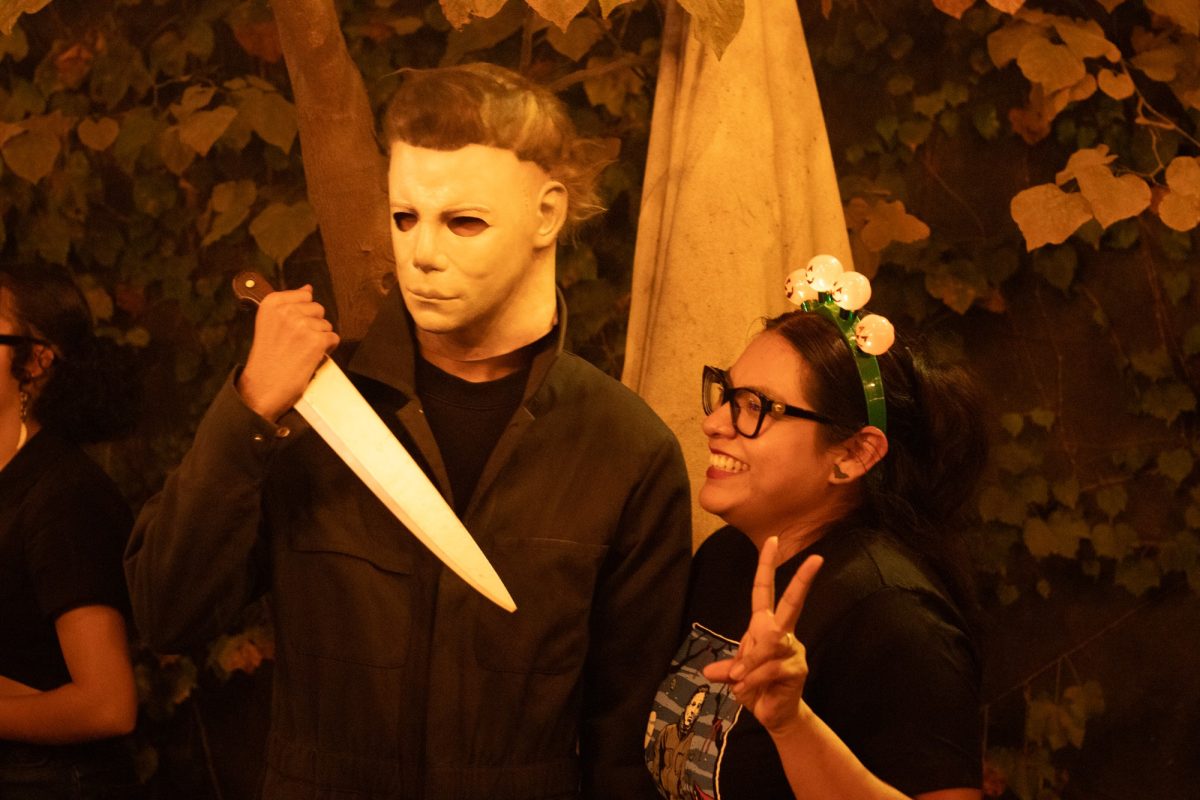 Roman Ikram dressed as Michael Myers, taking a picture with another customer. 