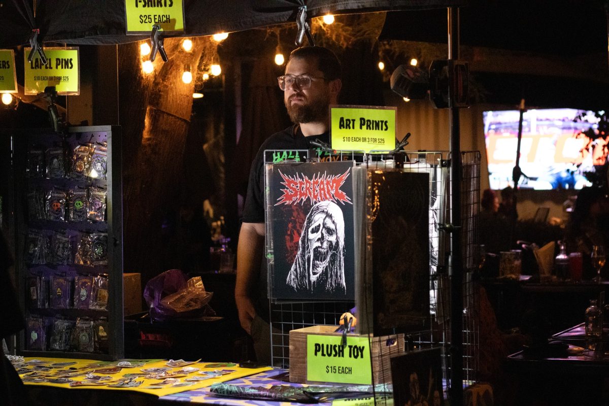 Vendor looking at customers looking over their pins and other items. 