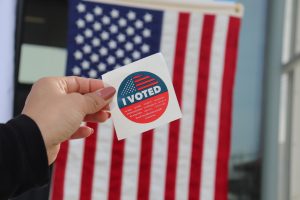 An "I Voted" sticker in front of the American flag. 