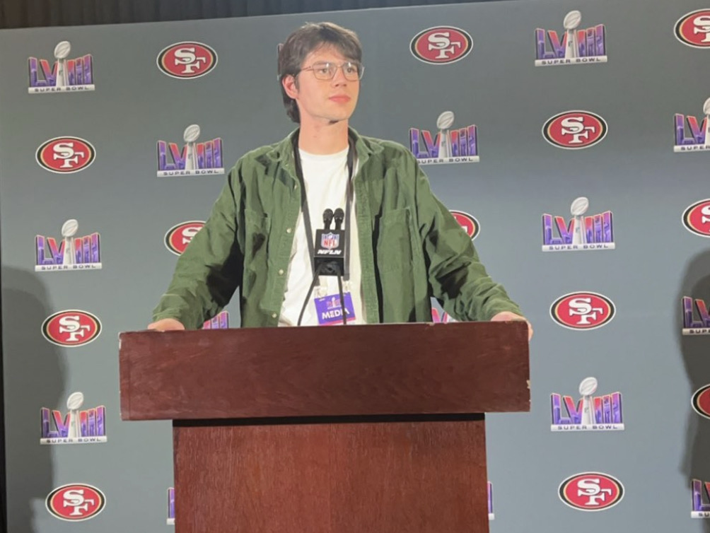 Theo Ash posing for a picture at the podium in the 49ers press room at Super Bowl LVIII on Feb. 7, 2024. Courtesy of Theo Ash.
